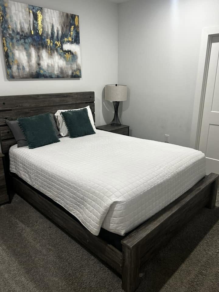 A bedroom with the bed made and surfaces cleared