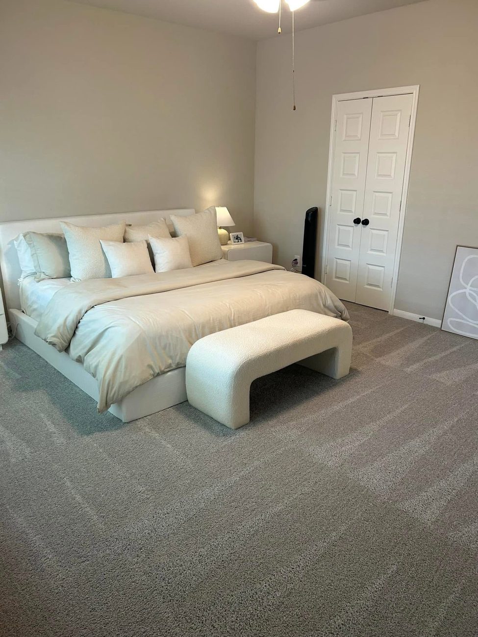A bright bedroom with fresh carpet and a made bed