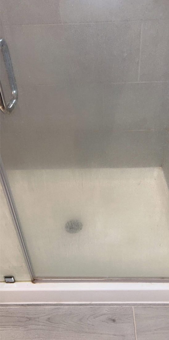 A shower screen clouded with soap scum before cleaning