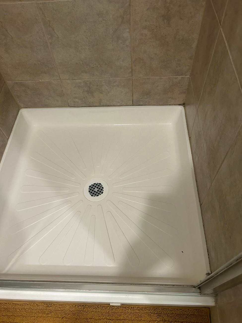A clean shower pan and tiled surround